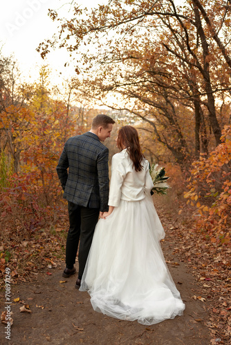 bride in white wedding dress and groom walking outdoor on natural background