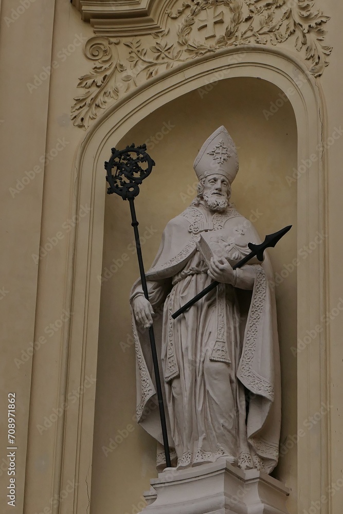 Statue of saint in bishops clothing with Crosier staff in right hand and something like broken spear in left hand. Located above front entrance of baroque Church Of Saint Peter and Paul in Rajhrad, CR Statue of saint in bishops clothing with Crosier staff in right hand and something like broken spear in left hand. Located above front entrance of baroque Church Of Saint Peter and Paul in Rajhrad, CR