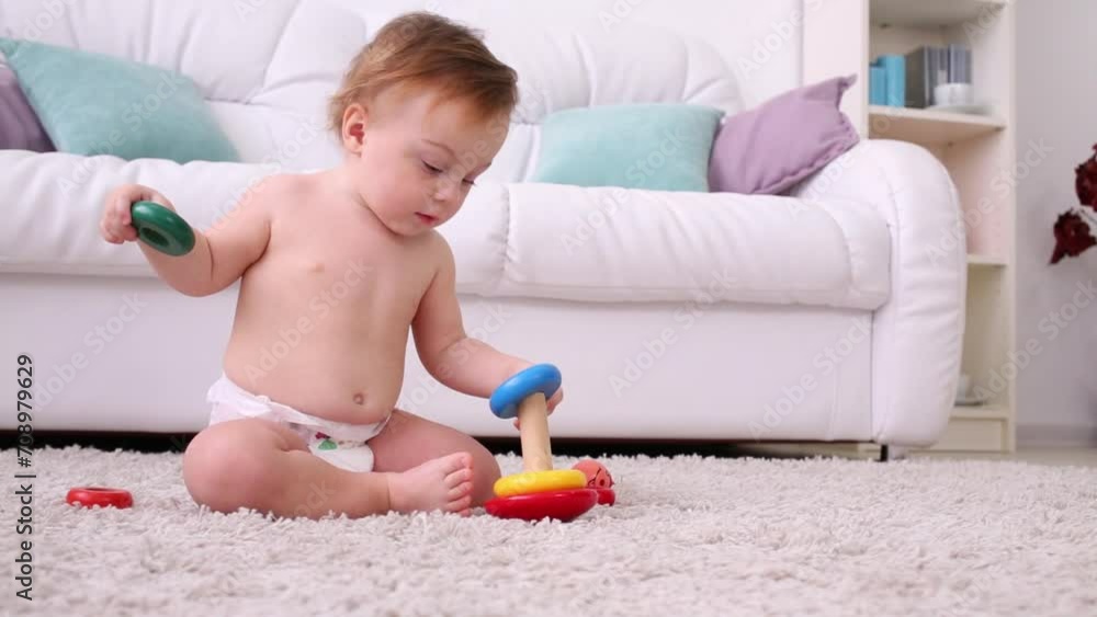 Little kid in diaper sits on carpet and plays with pyramid Little kid in diaper sits on carpet and plays with pyramid