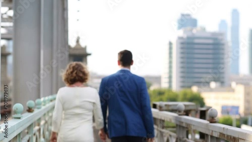 Back of pregnant woman and man walking together on railway bridge photo