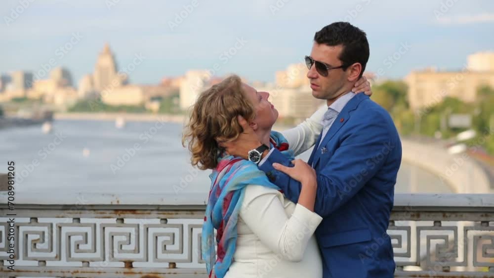 Pretty woman in white and young man embrace on bridge Pretty woman in white and young man embrace on bridge