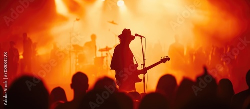 Guitar player on stage with concert crowd, in silhouette. photo