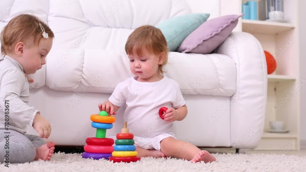 Two little kids on carpet play with pyramids near sofa Two little kids on carpet play with pyramids near sofa