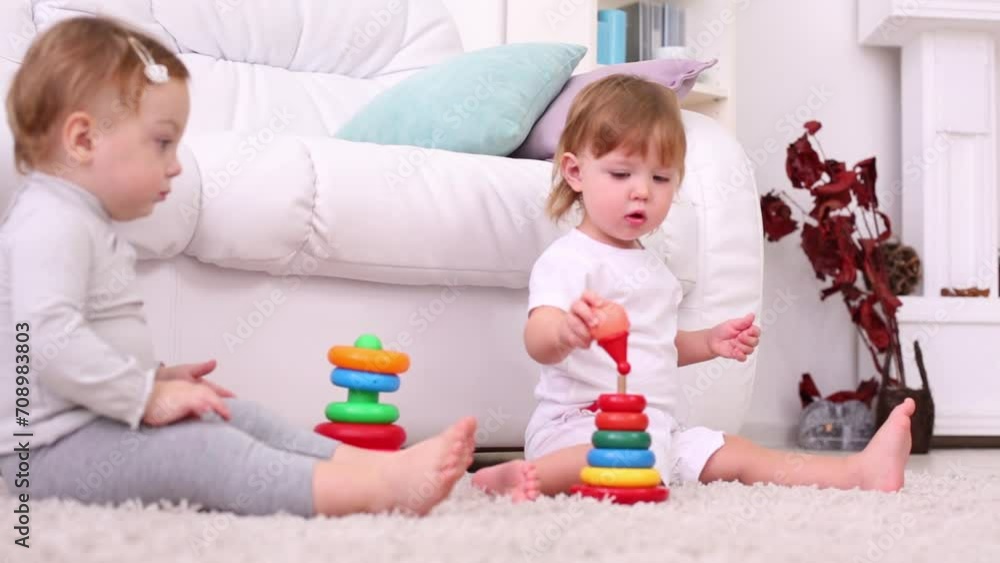 Two girls sit on carpet and play with pyramids near couch Two girls sit on carpet and play with pyramids near couch