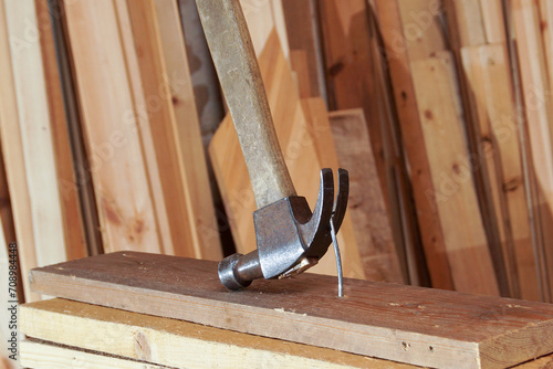 A carpenter's hammer and a nail being pulled out of a board. photo