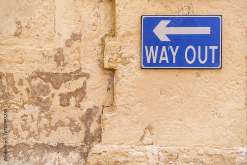 Color image of a Way Out blue sign on a wall.