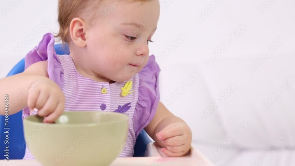 Little cute baby sits at highchair and eats porridge Little cute baby sits at highchair and eats porridge