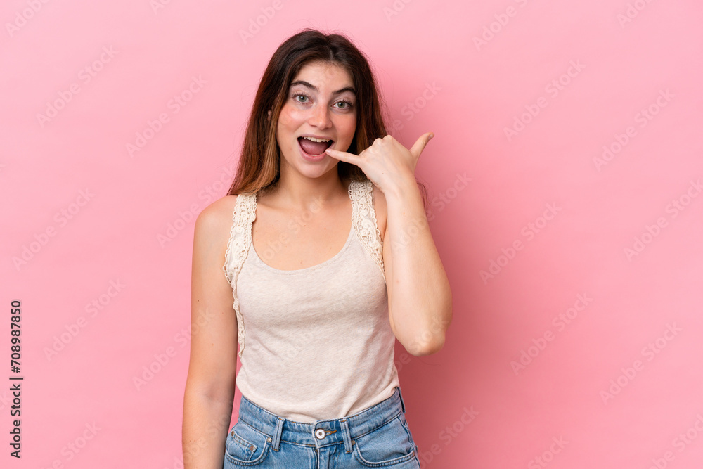 Young caucasian woman isolated on pink background making phone gesture. Call me back sign Young caucasian woman isolated on pink background making phone gesture. Call me back sign