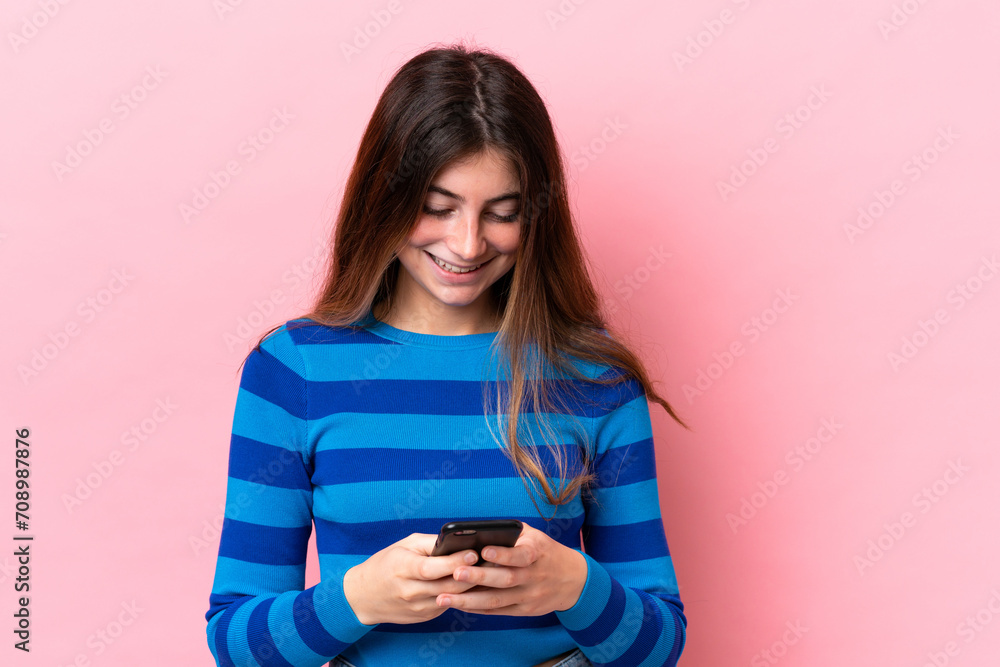Young caucasian woman isolated on pink background sending a message with the mobile Young caucasian woman isolated on pink background sending a message with the mobile