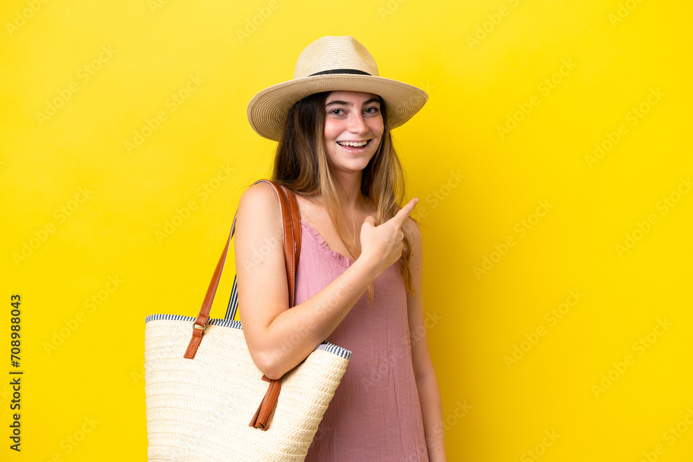 Young caucasian woman holding a beach bag isolated on yellow background pointing to the side to present a product Young caucasian woman holding a beach bag isolated on yellow background pointing to the side to present a product