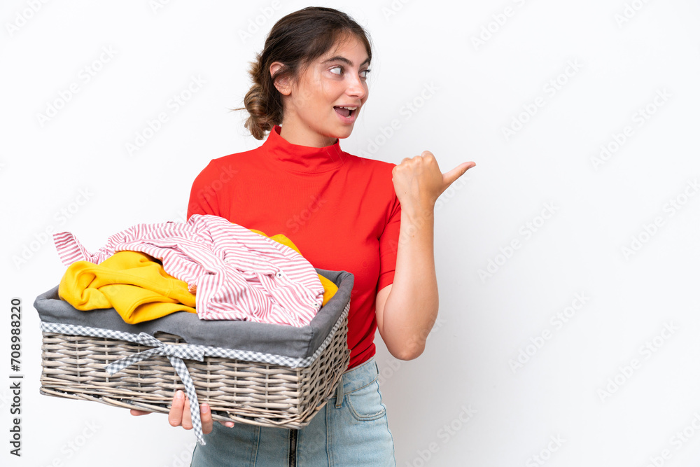 Young caucasian woman holding a clothes basket isolated on white background pointing to the side to present a product Young caucasian woman holding a clothes basket isolated on white background pointing to the side to present a product