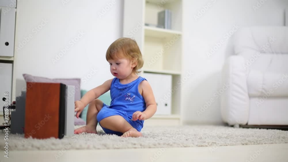 Cute kid in blue touches stereo system on carpet in room Cute kid in blue touches stereo system on carpet in room