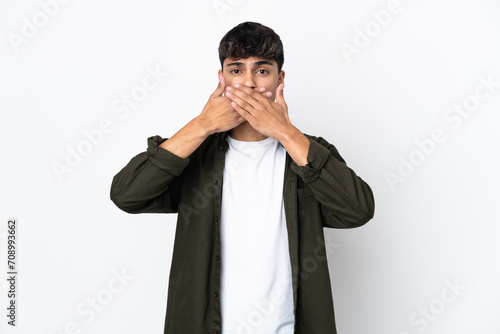 Young man over isolated white background covering mouth with hands