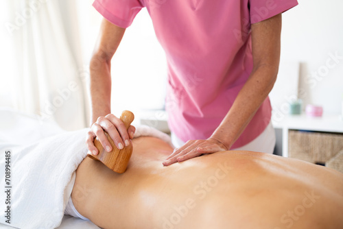 Massage therapist massaging back of client in physiotherapy clinic