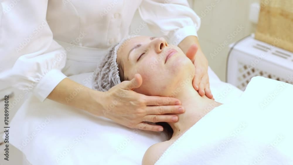 A cosmetologist gives a facial massage to a patient after a peeling procedure, biorevitalization, close up. A cosmetologist gives a facial massage to a patient after a peeling procedure, biorevitalization, close up.