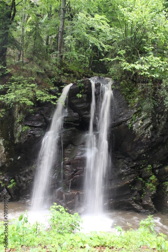 A majestic waterfall cascades amidst a vibrant  emerald forest.