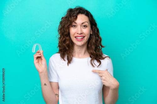 Young caucasian woman holding a envisaging isolated on blue background with surprise facial expression photo