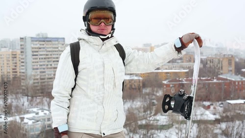 Girl snowboarder in helmet and sunglasses standing on hillside photo