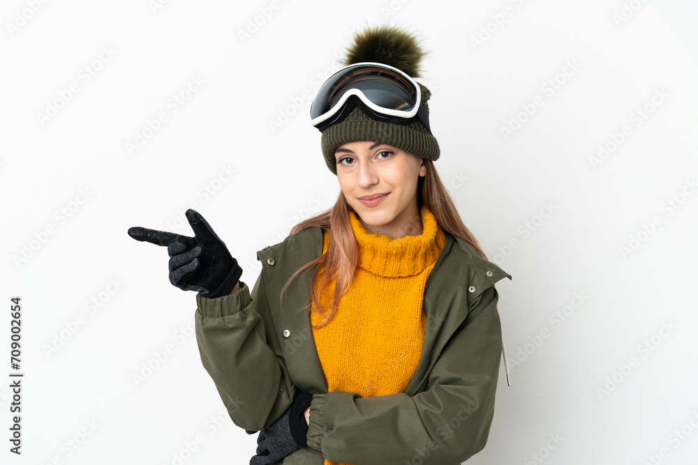 Skier caucasian woman with snowboarding glasses isolated on white background pointing finger to the side Skier caucasian woman with snowboarding glasses isolated on white background pointing finger to the side