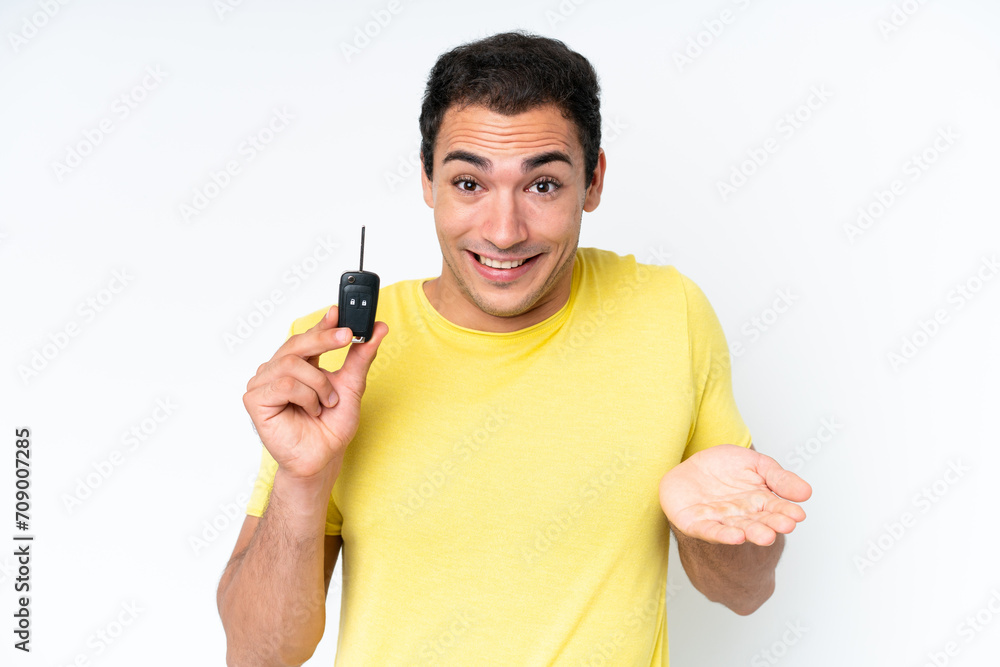 Young caucasian man holding car keys isolated on white background with shocked facial expression