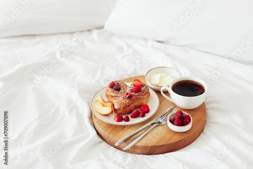 Wooden tray with romantic breakfast for Valentine's Day on white soft bed