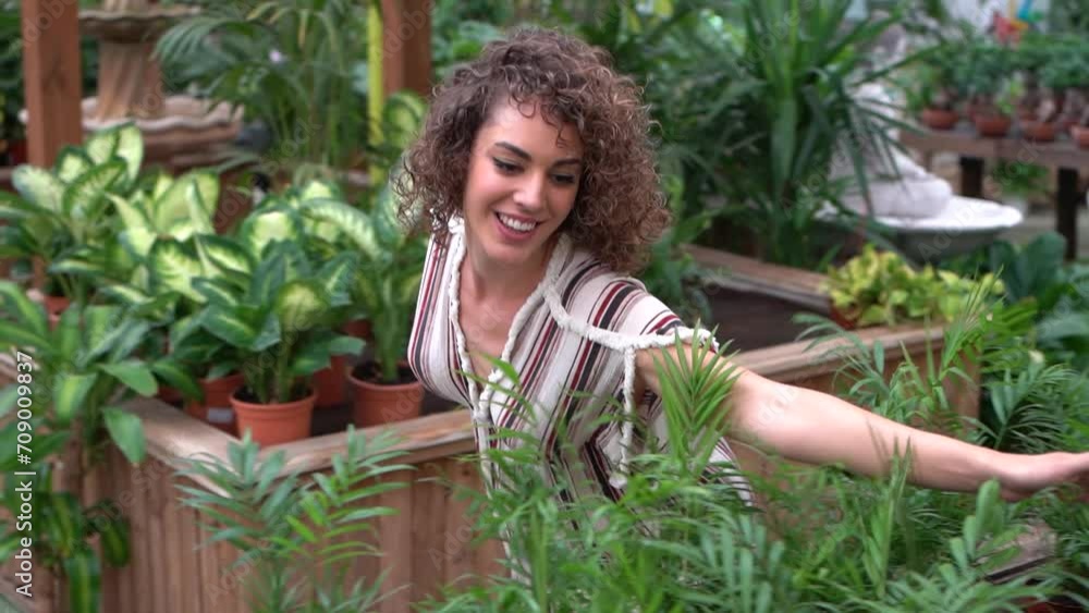 Young woman standing and enjoying while touching green potted plants in nursery Young woman standing and enjoying while touching green potted plants in nursery