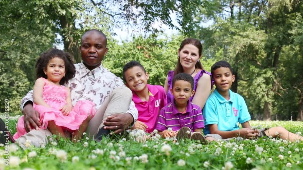 Parents with four children sitting in a clearing in the park Parents with four children sitting in a clearing in the park