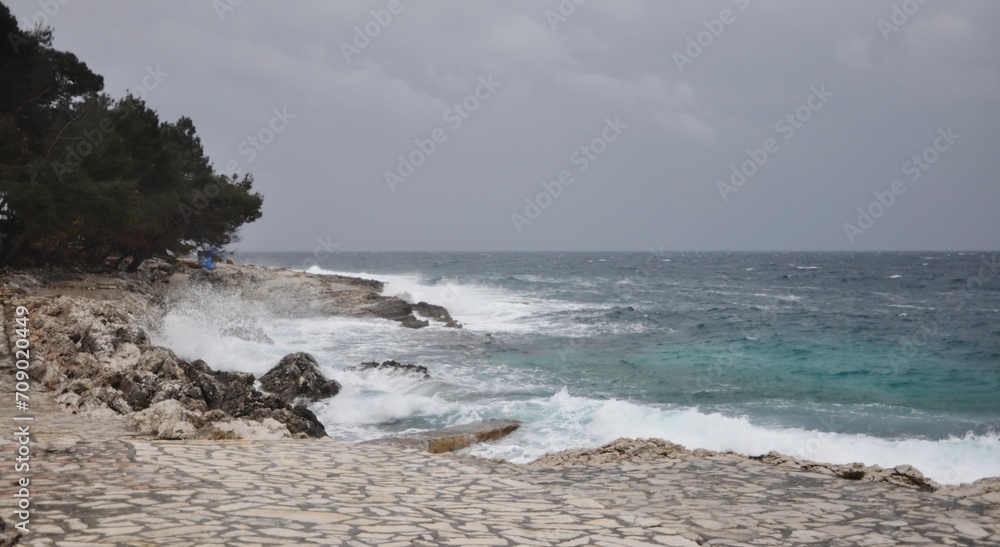 Huge Violent Waves Breaking on Rock Cliffs on Mali Losinj coastline. Losinj island in Croatia, Nord coast in Europe.Dramatic seascape. Storm in the ocean, big waves hitting the rocks. 