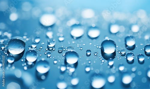 close-up, macro photo of a group of water drops on a blue surface with the water drops blurred due to the open aperture and selective focus