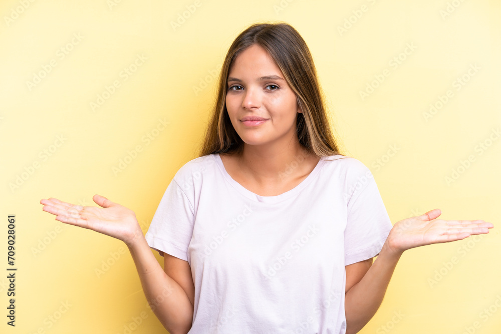 Young caucasian woman isolated on yellow background having doubts Young caucasian woman isolated on yellow background having doubts
