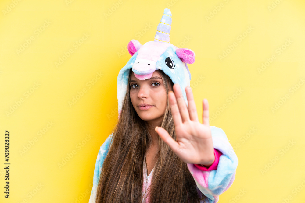 Young caucasian woman wearing a unicorn pajama isolated on yellow background making stop gesture Young caucasian woman wearing a unicorn pajama isolated on yellow background making stop gesture