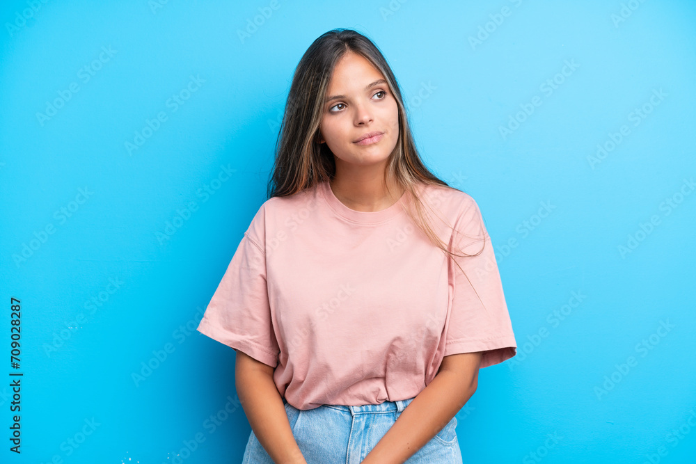 Young caucasian woman isolated on blue background looking to the side Young caucasian woman isolated on blue background looking to the side