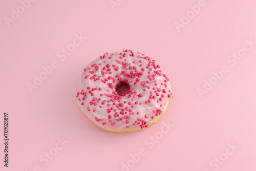 Sugary food background. Strawberry doughnut with pink icing and white stripes isolated on pink background. Top view.