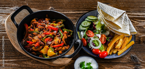 Photos Fajita with peppers and onions served on a hot iron skillet