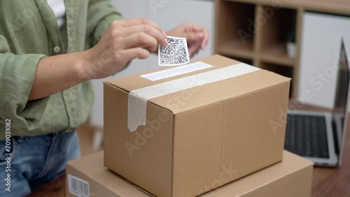 close up With precision, a woman online shopper attaches a qr code label to a cardboard parcel, signaling her intent to return and receive a refund.  photo