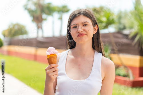 Young pretty Ukrainian woman with a cornet ice cream at outdoors with sad expression