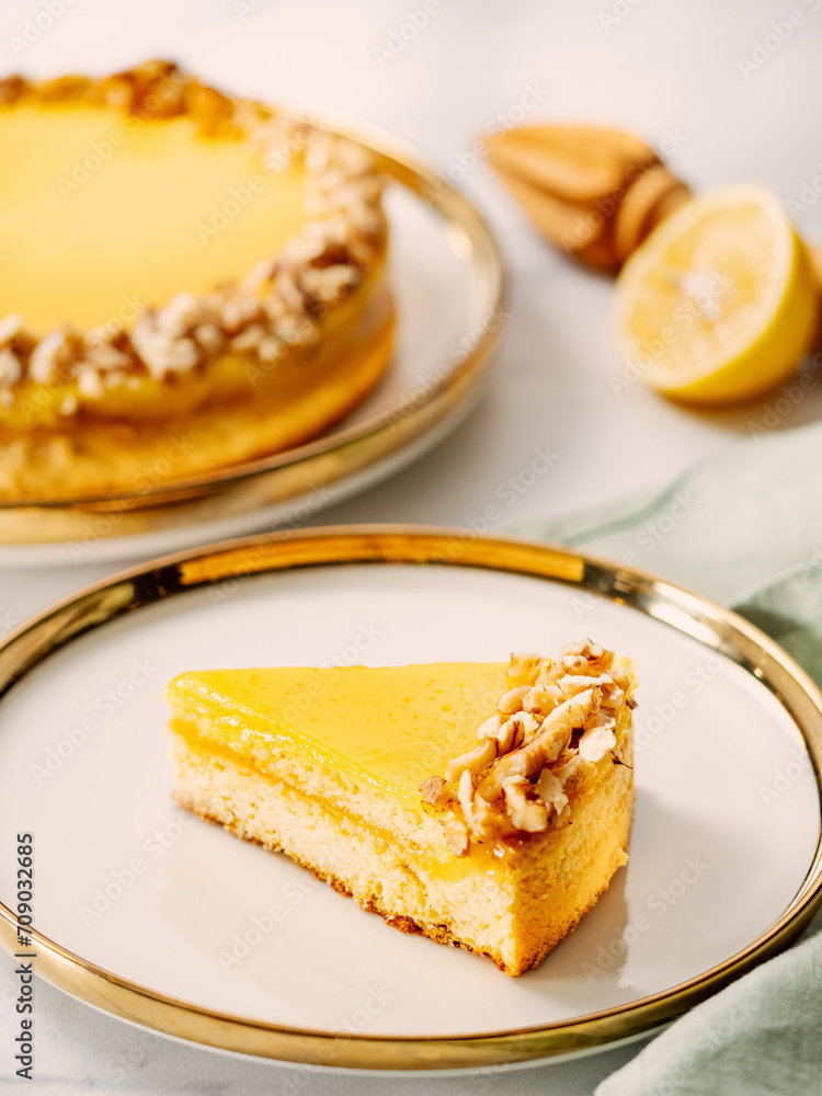 Piece of delicious vegan lemon tart or lemon cake, modernly decorated with walnuts on aesthetic plate. Aesthetic of traditional classic french lemon pie with lemon curd recipe. Vertical, copy space