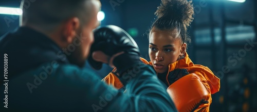 A young lady and her sports coach are engaging in kickboxing training for fitness and empowerment, emphasizing motivation and healthy exercise in the gym. © AkuAku