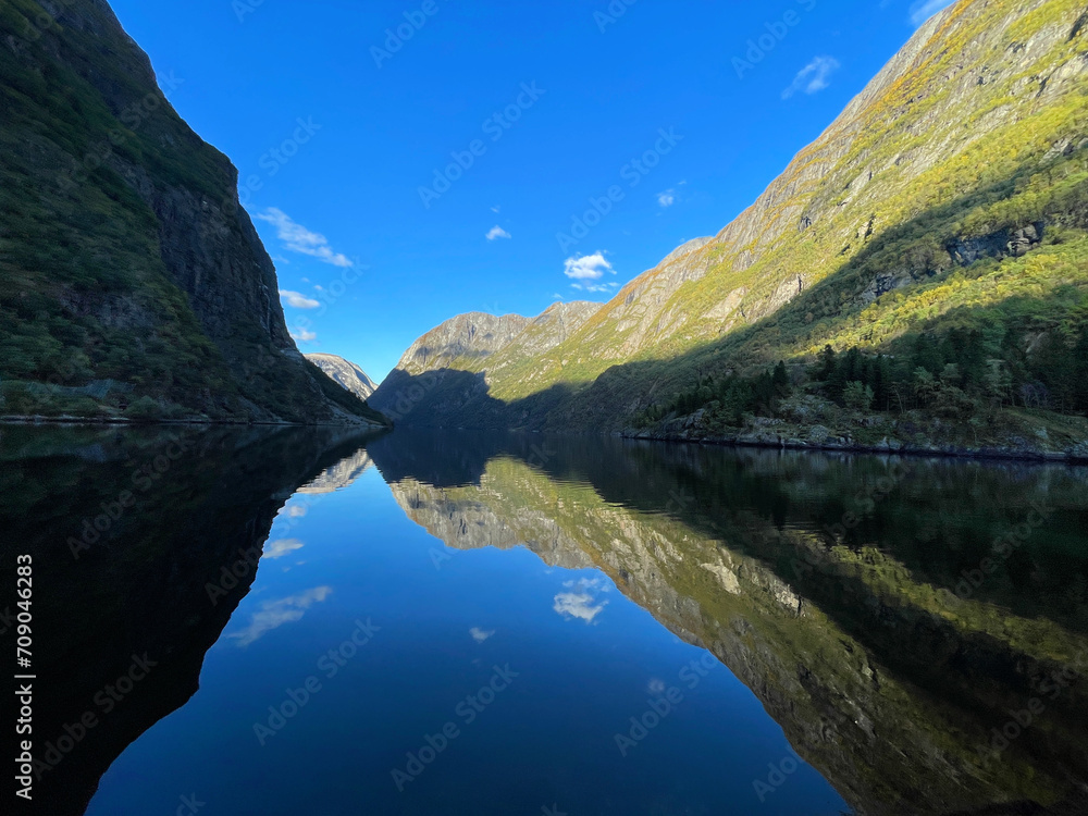 Symmetrical reflections of the fjord in the afternoon, view from Gudvangen ferry pier