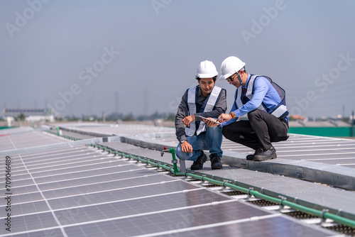 Engineers walking on roof inspect and check solar cell panel by hold equipment box and radio communication ,solar cell is smart grid ecology energy sunlight alternative power factory concept  © APchanel