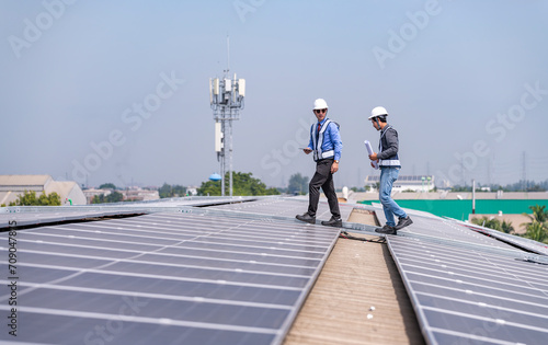 Engineers walking on roof inspect and check solar cell panel by hold equipment box and radio communication ,solar cell is smart grid ecology energy sunlight alternative power factory concept 