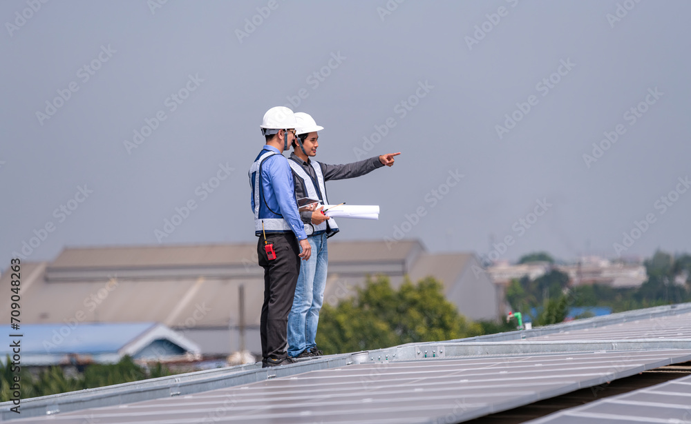 Engineers walking on roof inspect and check solar cell panel by hold equipment box and radio communication ,solar cell is smart grid ecology energy sunlight alternative power factory concept	