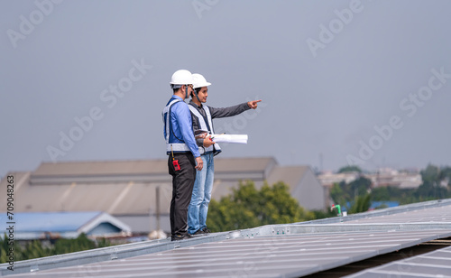 Engineers walking on roof inspect and check solar cell panel by hold equipment box and radio communication ,solar cell is smart grid ecology energy sunlight alternative power factory concept  © APchanel