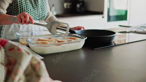 Mujer mayor en la cocina remojando pan en leche y huevo para hacer torrijas tradicionales para su familia en las fiestas de semana santa photo