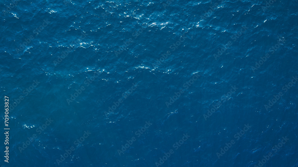 Aerial View Of Surface Of deep dark blue Sea with reflection of the sun's rays as background for page, template or web banner