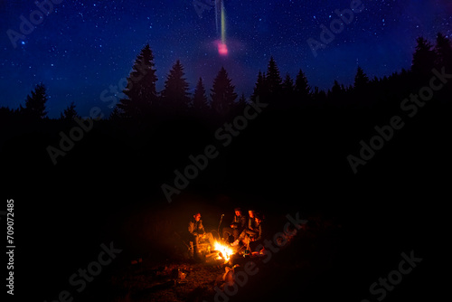 Group of people near the fireplace in the night forest