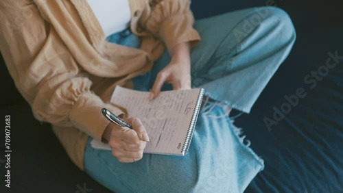 Hands, writing in notepad and person in home on sofa for creative idea, planning and schedule agenda. Inspiration, notes and closeup on couch with journal, to do list and pen to study in living room photo