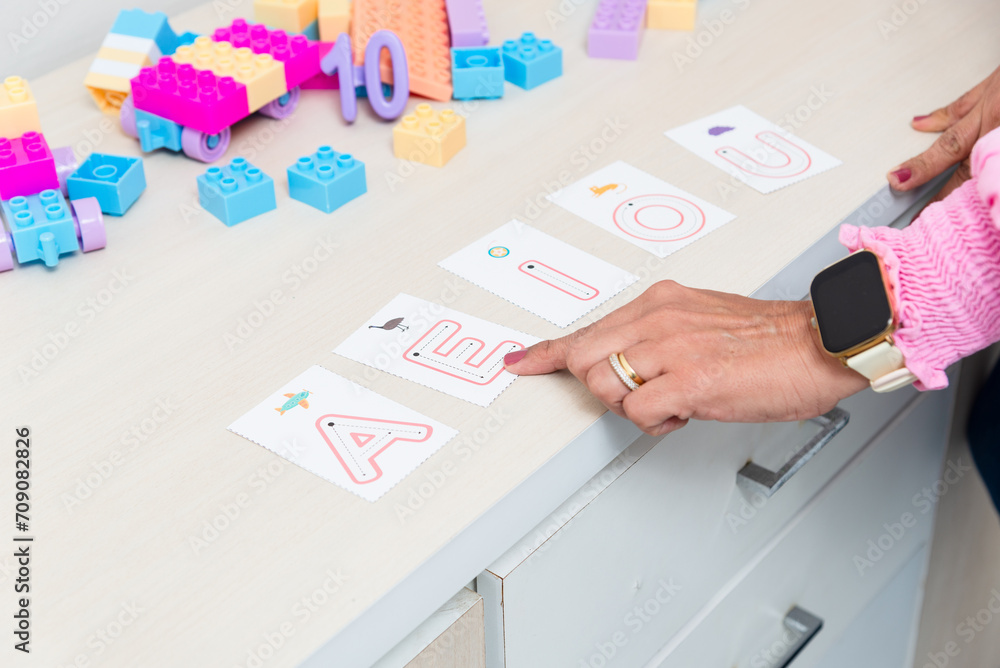 © Thales - Hand of a psychopedagogue showing letters with letters of the alphabet. Educational help.