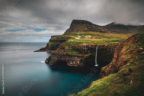 long exposure of mulafossur waterfall at faroe islands on a cloudy day by atlantic ocean photo