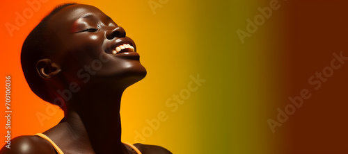 Close-up of a smiling woman with dark skin, her vibrant skin glowing under bright light.